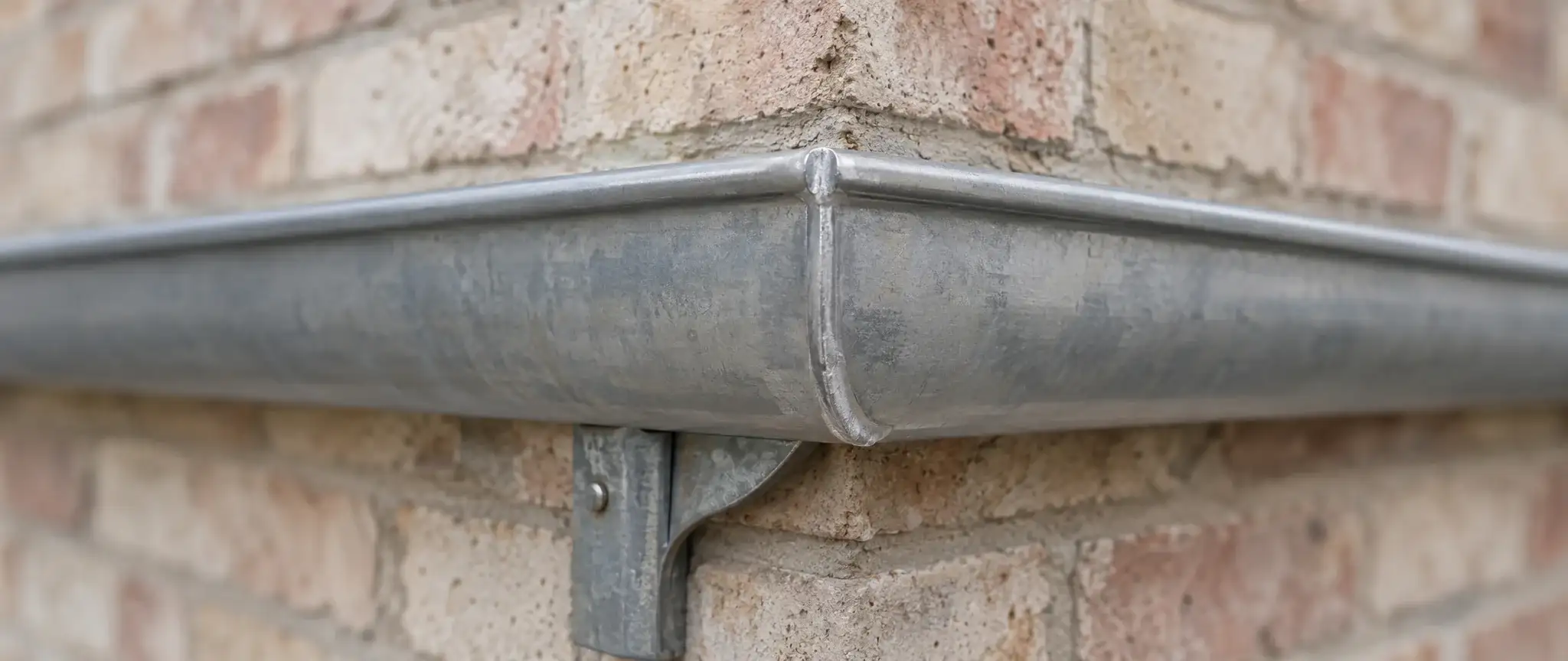 Zinguerie à Gravelines : angle d’une gouttière demi-ronde en zinc avec sa soudure et son crochet de fixation